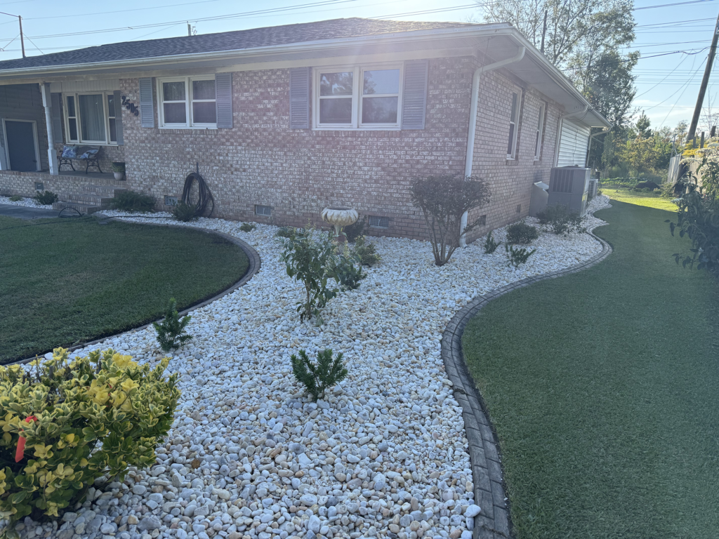 Rock landscaping with white decorative stones surrounding a well-maintained lawn and brick home in Surfside Beach, SC, enhancing curb appeal and providing low-maintenance outdoor aesthetics.