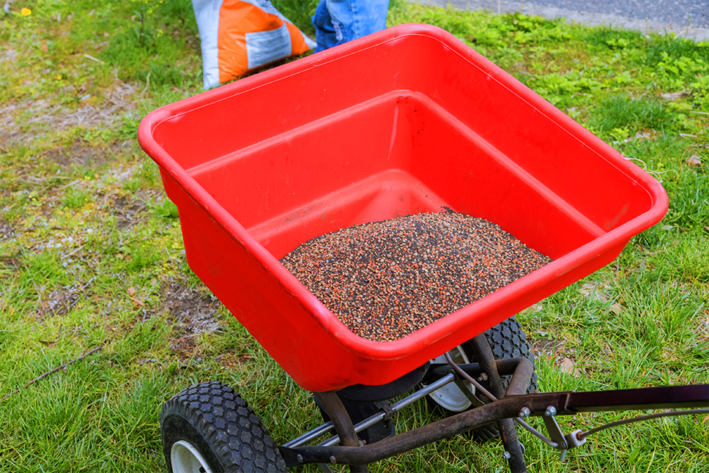 Red wheelbarrow filled with lawn grass seeds, ready for fertilization and weed control services in Surfside Beach, SC.