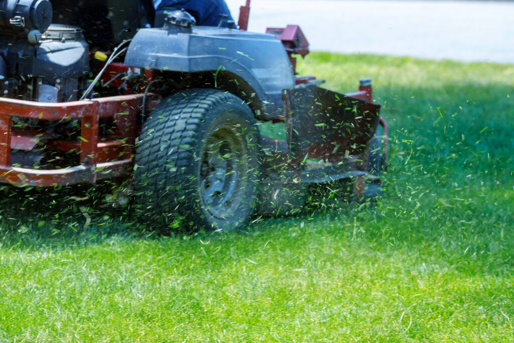 Red commercial lawn mower cutting grass in a well-maintained lawn, demonstrating professional mowing services for commercial properties in Market Common, SC.