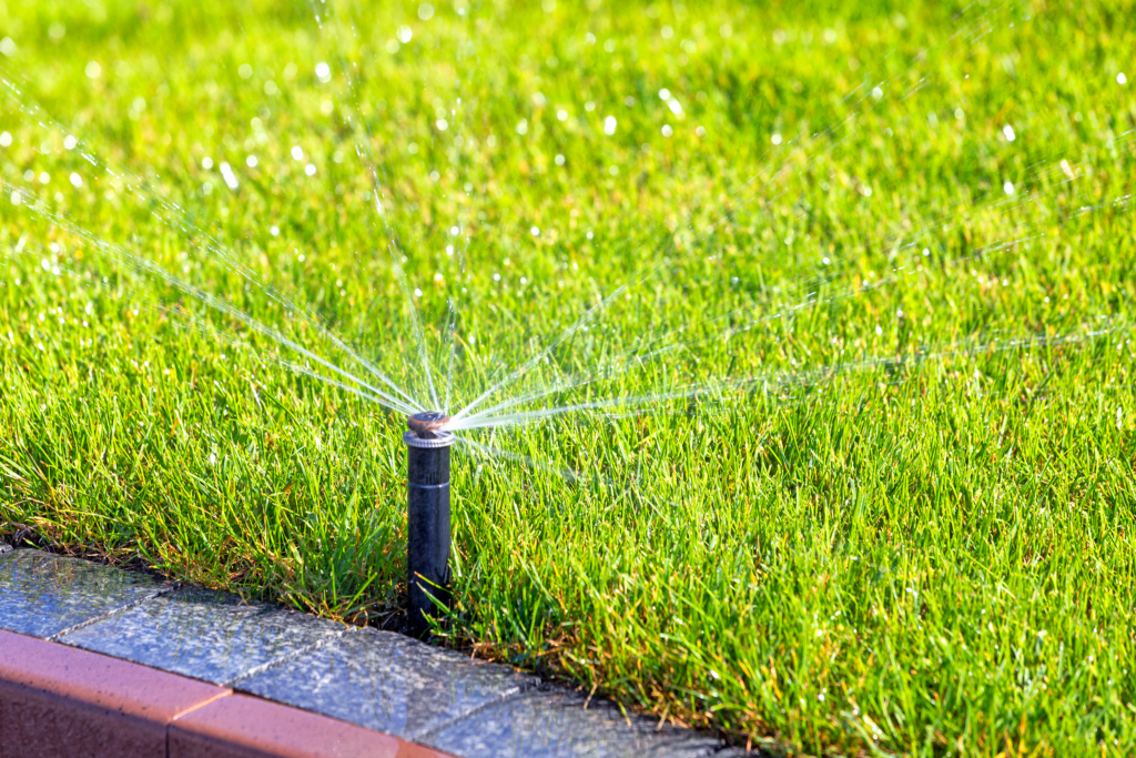 Automatic sprinkler system spraying water on lush green grass, illustrating effective irrigation for healthy landscapes in Carolina Forest, SC.
